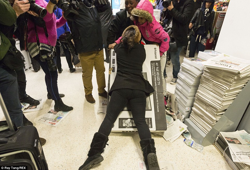 In shocking scenes, a woman desperately clung to a  TV after a brawl broke out at the Asda store in Wembley over the cut-price item